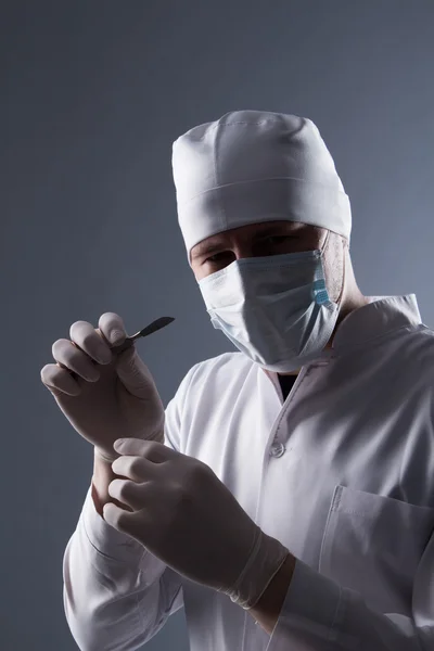 Mężczyzna lekarz w WPR, maska i gumowe rękawice medyczne, trzymając głowy — Zdjęcie stockowe