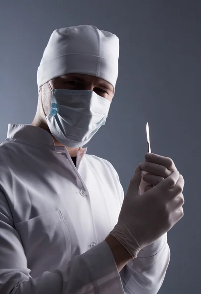 Male doctor in cap, mask and rubber medical gloves holding scalp — Stock Photo, Image