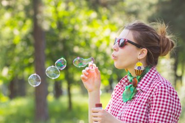 Neşeli güzel esmer kız bardaklarda sabun köpüğü üfleme