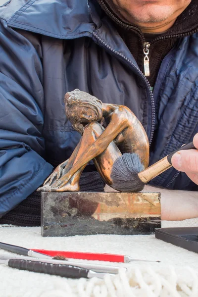 Mãos de escultor segurar escultura de cobre e limpá-lo com escova — Fotografia de Stock