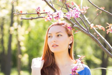 Bahar flowe arasında mavi elbiseli güzel kızıl saçlı kız