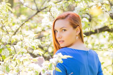 Bahar flowe arasında mavi elbiseli güzel kızıl saçlı kız