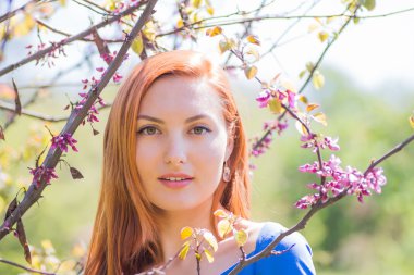 Bahar flowe arasında mavi elbiseli güzel kızıl saçlı kız