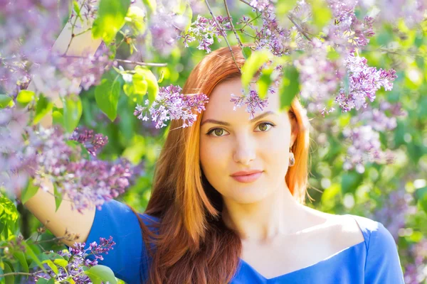 Bela menina de cabelos vermelhos em vestido azul entre flowe primavera — Fotografia de Stock