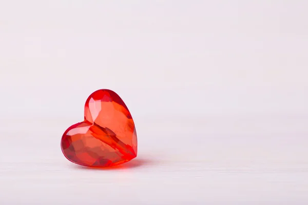 Un coeur facetté rouge en plastique sur fond clair — Photo