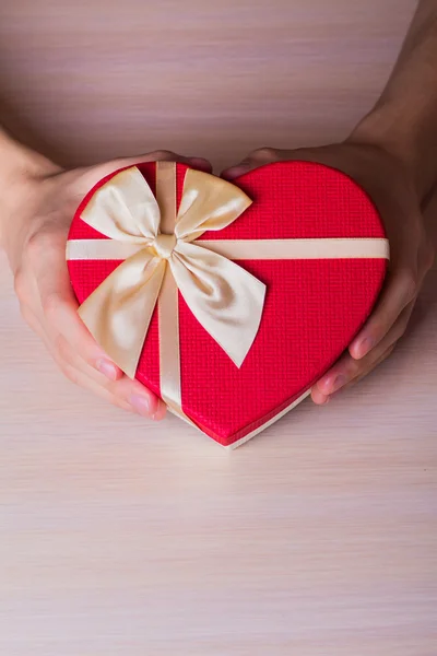 Kırmızı hediye tutan iki erkek eli kalp şeklinde kutu — Stok fotoğraf