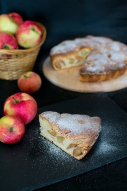Siyah arka planda elmalı turta. Üzerine pudra şekeri serpilmiş..