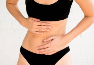 Beyaz arka planda kadın göbeği. Karın ağrısı var. Dikey çerçeve. Gürültü efektli seçici odak fotoğrafı