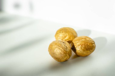 Beyaz arka planda üç altın rengi ceviz. Fotoğraf seçici odak ve gürültü efektiyle çekildi