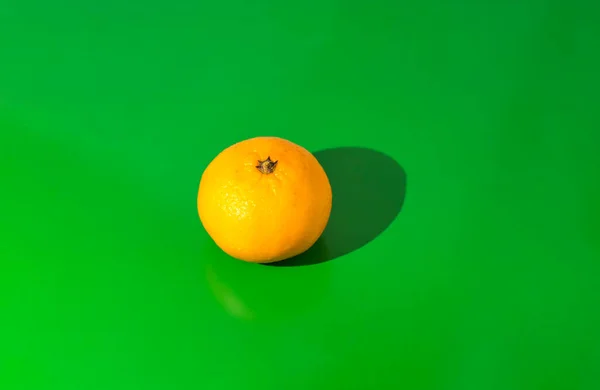 Tangerine on green background centered. Photo taken with selective focus and noise effect