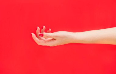 Kırmızı arka planda bir kadın eli. Kırmızı manikür. Fotoğraf seçici bir odak ile çekildi ve gürültü etkisi var..
