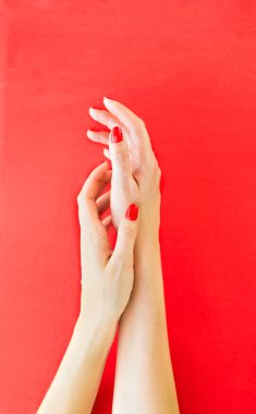 Kırmızı arka planda bir kadın eli. Fotoğraf yatay olacak. Fotoğraf seçici odak ve gürültü efektiyle çekildi