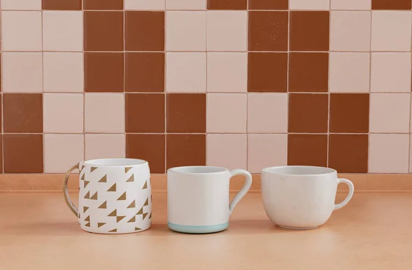三个不同的咖啡杯与墙壁并排放在厨房台面上 关闭前视图 3D渲染 — 图库照片