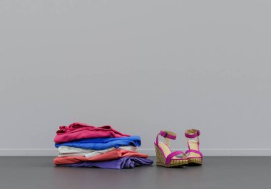 Bir çift sıradan kadın ayakkabısı ve katlanmış çamaşırları, kumaşı ve aksesuarları fotokopi alanı olan gri bir iç odada.