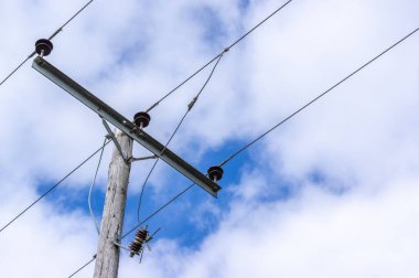Tahta telgraf direği tarzı güç hattı bulutlu bir gökyüzü ile üç kablo.