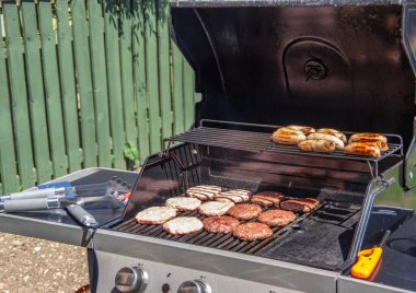 Güneşli bir günde hamburger, sosis ve çatal bıçakla ızgara..