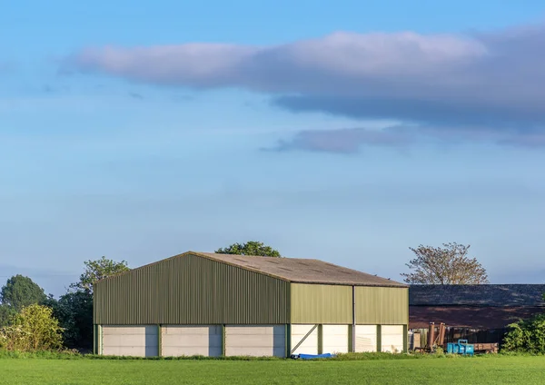 Prefabricated farm building in a rural setting on a sunny day with blue sky.