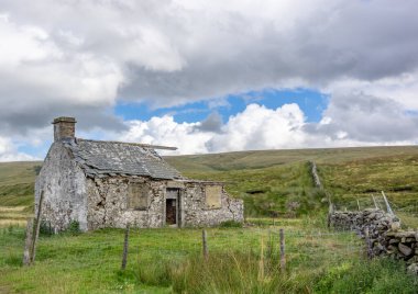 Gökyüzü bulutlu Yorkshire Dales manzarasında terkedilmiş bir çiftlik evi inşa edildi..