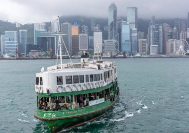 Hong Kong, Çin, 06 / 02 / 2017 - Arka planda Hong Kong silueti ile limandan geçen yeşil ve beyaz feribot.