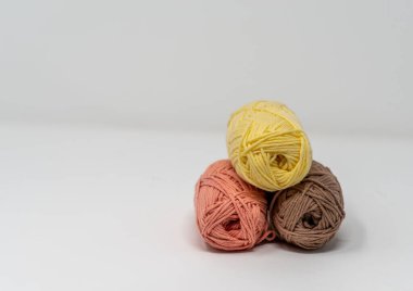 Düz beyaz bir arkaplanda, kopyalama alanı olan üç renkli yün yumak..