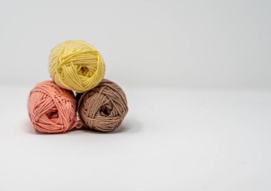 Düz beyaz bir arkaplanda, kopyalama alanı olan üç renkli yün yumak..