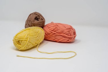 Düz beyaz bir arkaplanda, kopyalama alanı olan üç renkli yün yumak..