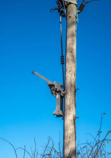 青い空を背景にワイヤーと絶縁体と木製の電信柱 — ストック写真