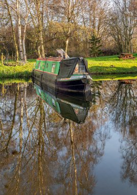 Melbourne, Doğu Yorkshire, İngiltere, 01 / 12 / 2020 - Güneşli bir günde Melbourne Arm 'a demirlemiş Kanal Dar botları durgun suda yansımalarla.