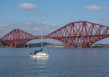 Güney Queensferry, Edinburgh, İskoçya 7 Eylül 2021 - Güneşli bir günde arka planda Forth Köprüsü olan küçük bir yelkenli.