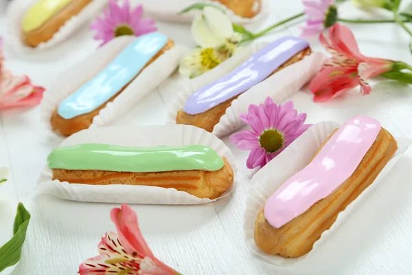 Eclairs with glaze and flowers — Stock Photo, Image