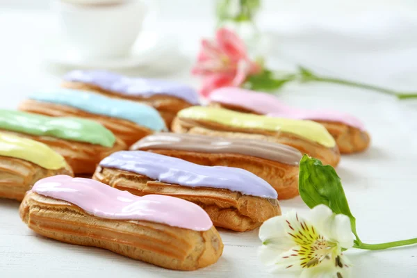 Eclairs with glaze and flowers — Stock Photo, Image