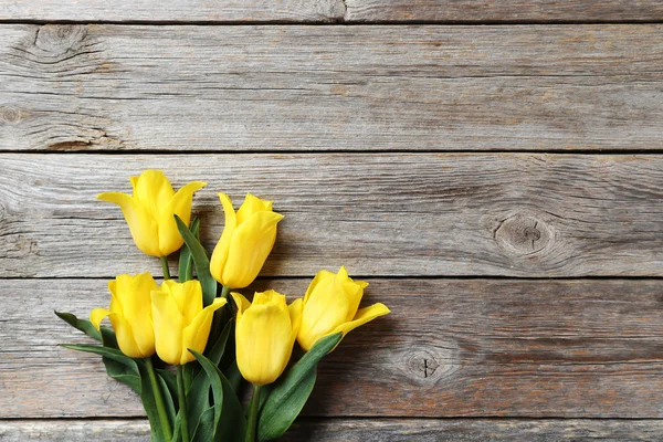 Ramo de tulipanes amarillos sobre una mesa de madera — Foto de Stock