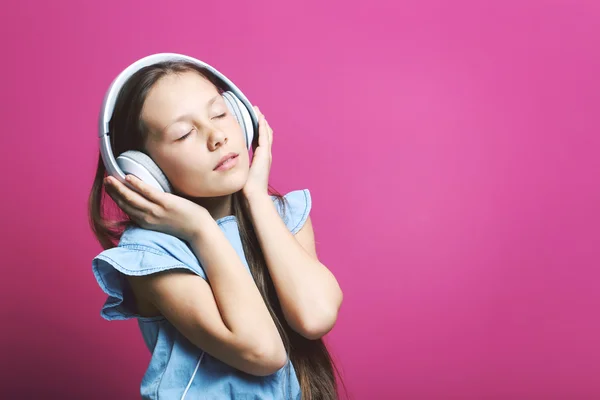 年轻的女孩，戴着耳机粉红色背景的肖像 — 图库照片