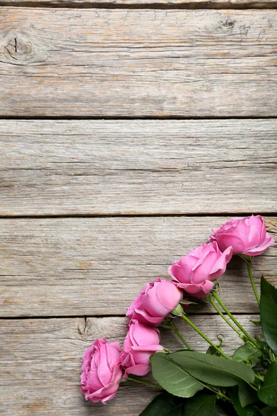 Hermosas rosas rosadas sobre mesa de madera — Foto de Stock