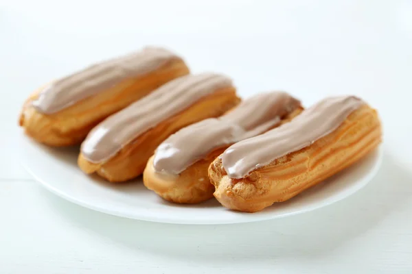 Eclairs con esmalte en una mesa blanca — Foto de Stock