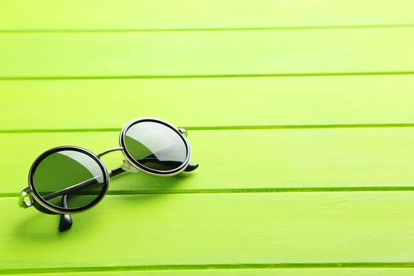 Чорні сонцезахисні окуляри на зеленому столі — стокове фото