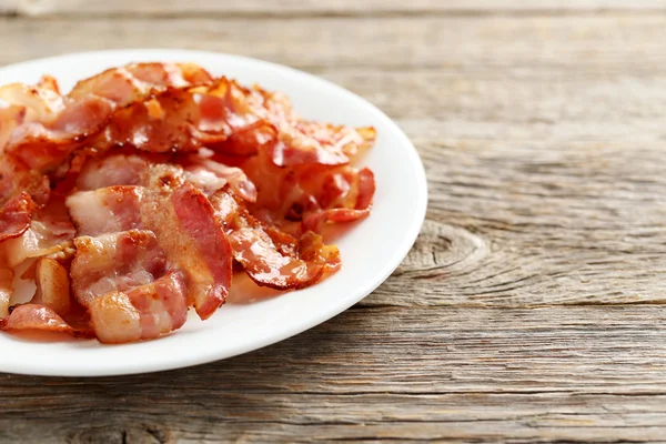 Tiras crujientes de tocino en el plato — Foto de Stock