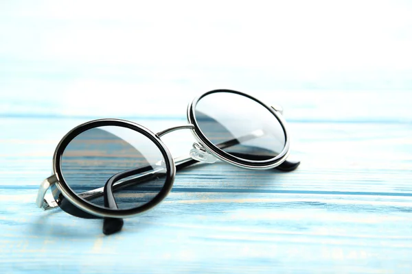 Óculos de sol pretos em uma mesa azul — Fotografia de Stock