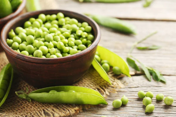 Groene erwten op houten tafel — Stockfoto