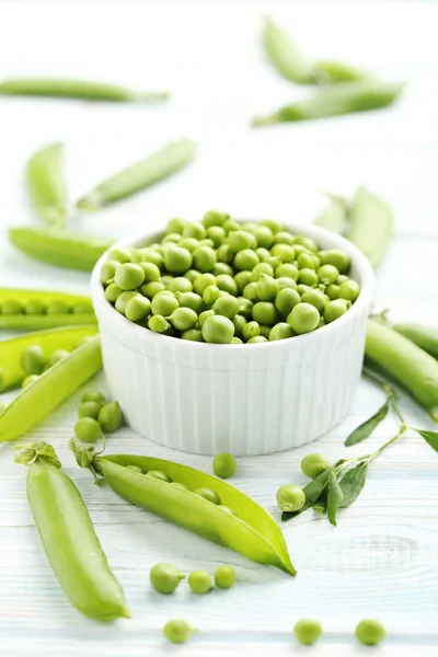Green peas on wooden table — Stock Photo, Image