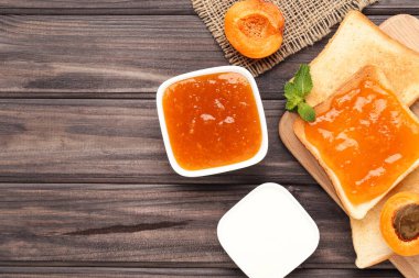 Kayısı reçelli tost ve ahşap masada krema.