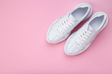 Pembe arka planda bir çift beyaz ayakkabı