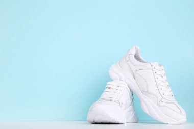 Mavi arkaplanda bir çift beyaz ayakkabı