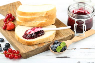 Reçelli taze ekmek ve beyaz tahta masada taze böğürtlen.