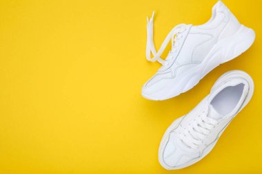 Pair of white shoes on yellow background clipart