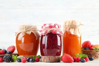 Cam kavanozlarda tatlı reçel ve beyaz arka planda olgun böğürtlen