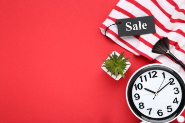 Yeşil bitkili saat, kırmızı arkaplanda etiket ve makyaj fırçası