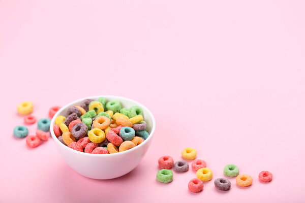 Colorful corn rings in bowl on pink background