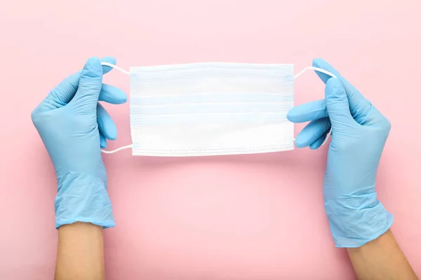 Medicine face mask and female hands in gloves on pink background