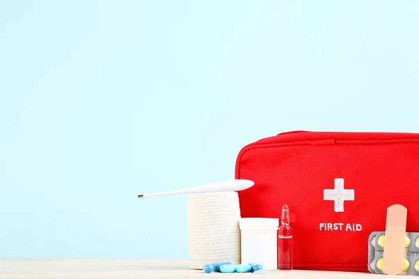 First aid kit with medical supplies on mint background